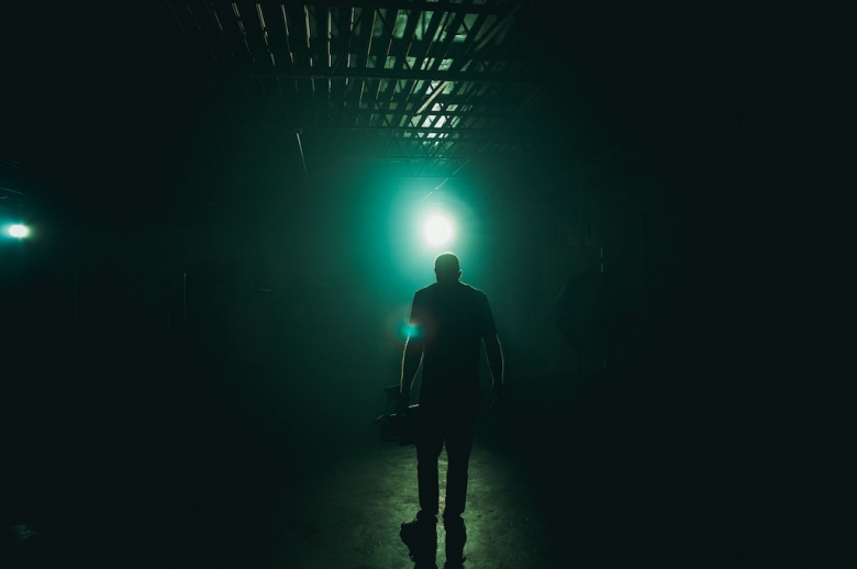 Person standing on a stage, backlit by a green light